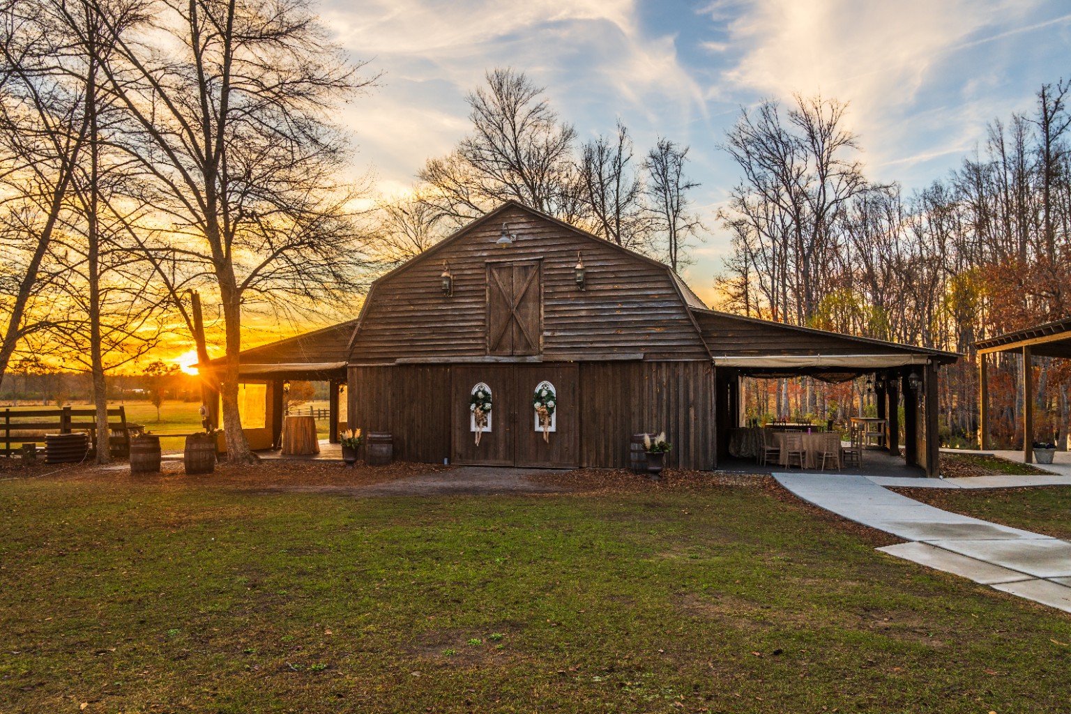 The wooden barn at Wildhorse at Parker Farms surrounded by trees at sunset
