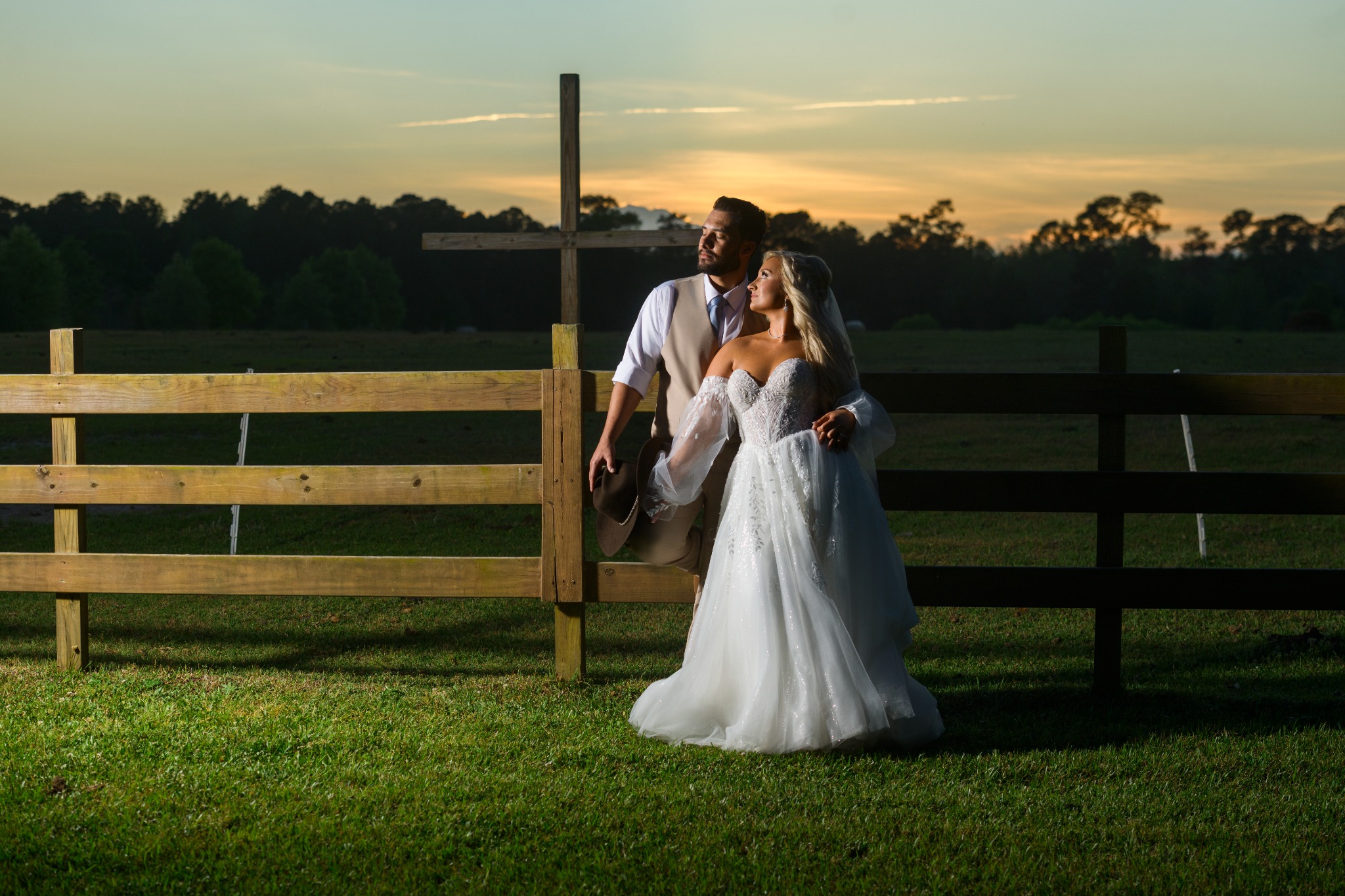 Newlyweds photographed beside the field cross at sunset at Wildhorse at Parker Farms